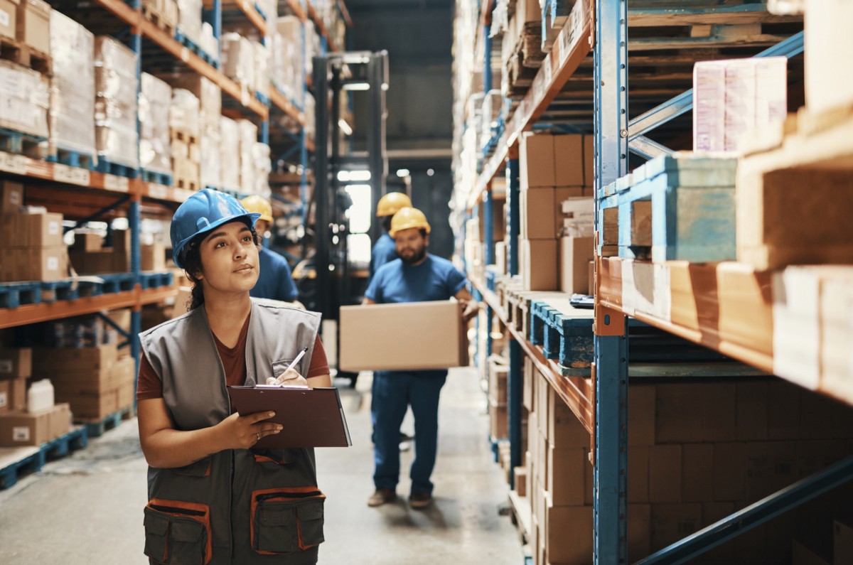 Woman checking inventory with clipboard at Mane Shipping warehouse for shipping services near Utah.